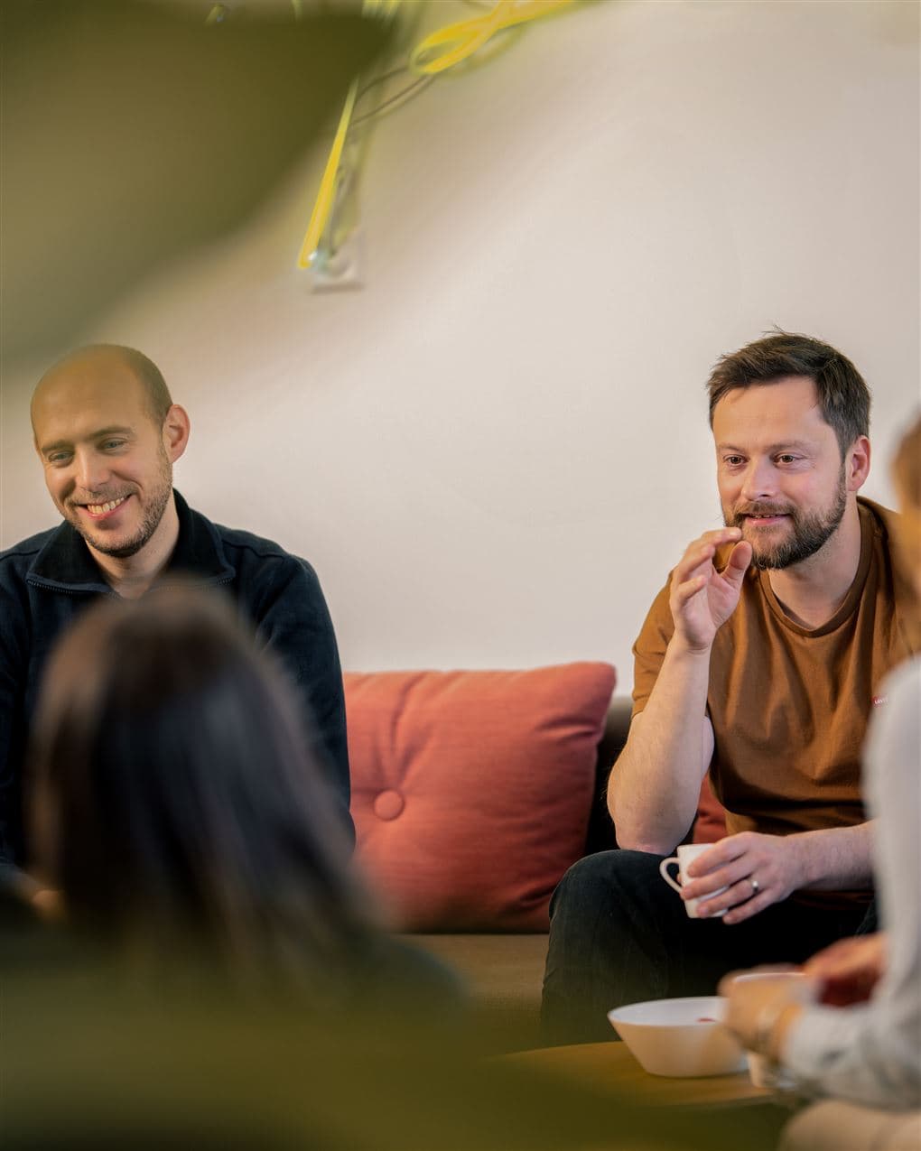 Drei Personen sitzen im Gespräch auf einem Sofa in einem Büro und tauschen sich über ein Projekt aus.